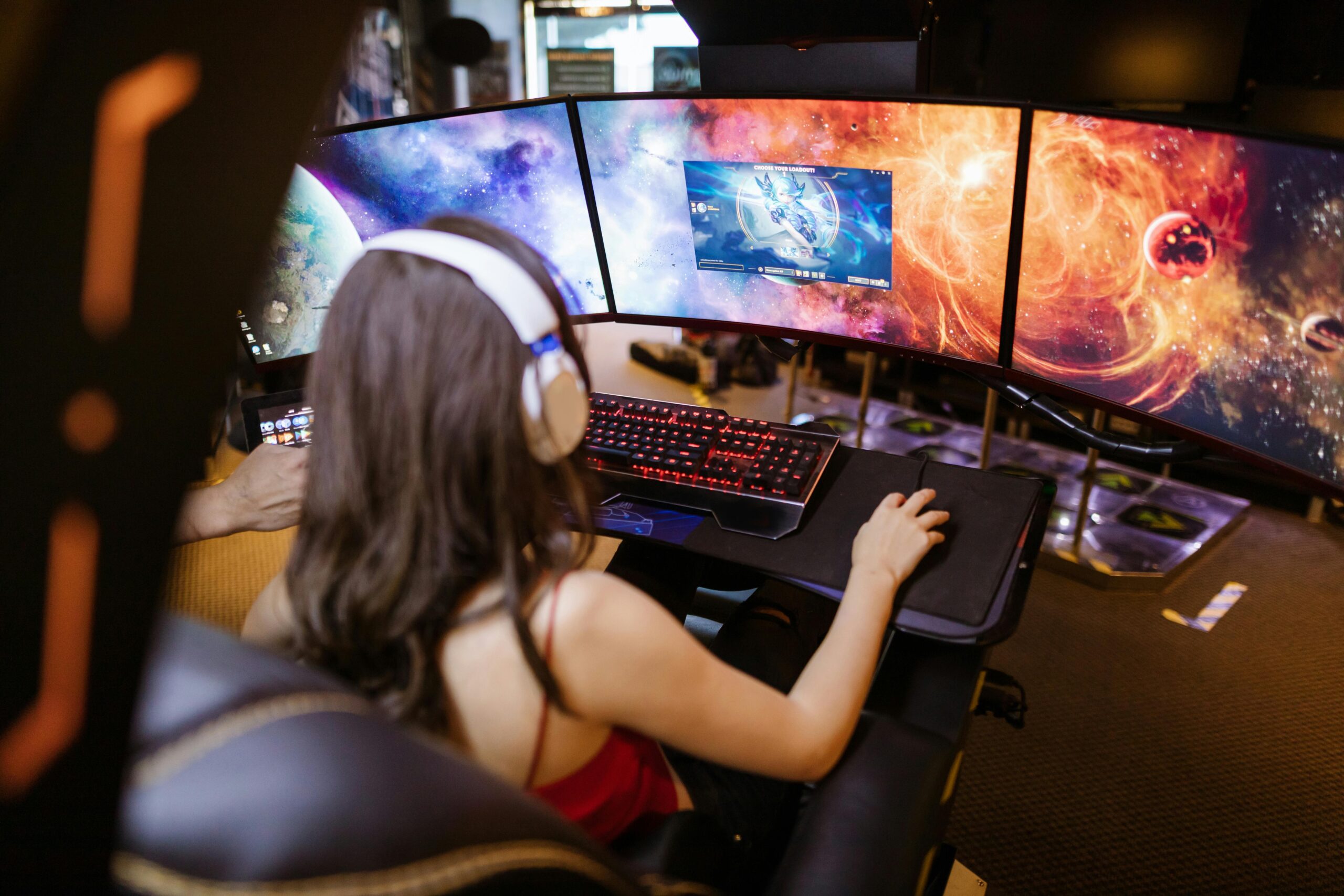 Gamer girl playing League of Legends on three monitors